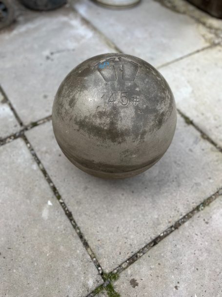 A weathered metallic sphere resting on a stone patio.