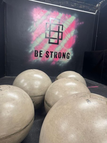 Large concrete balls in a gym with the text "BE STRONG" on the wall behind.